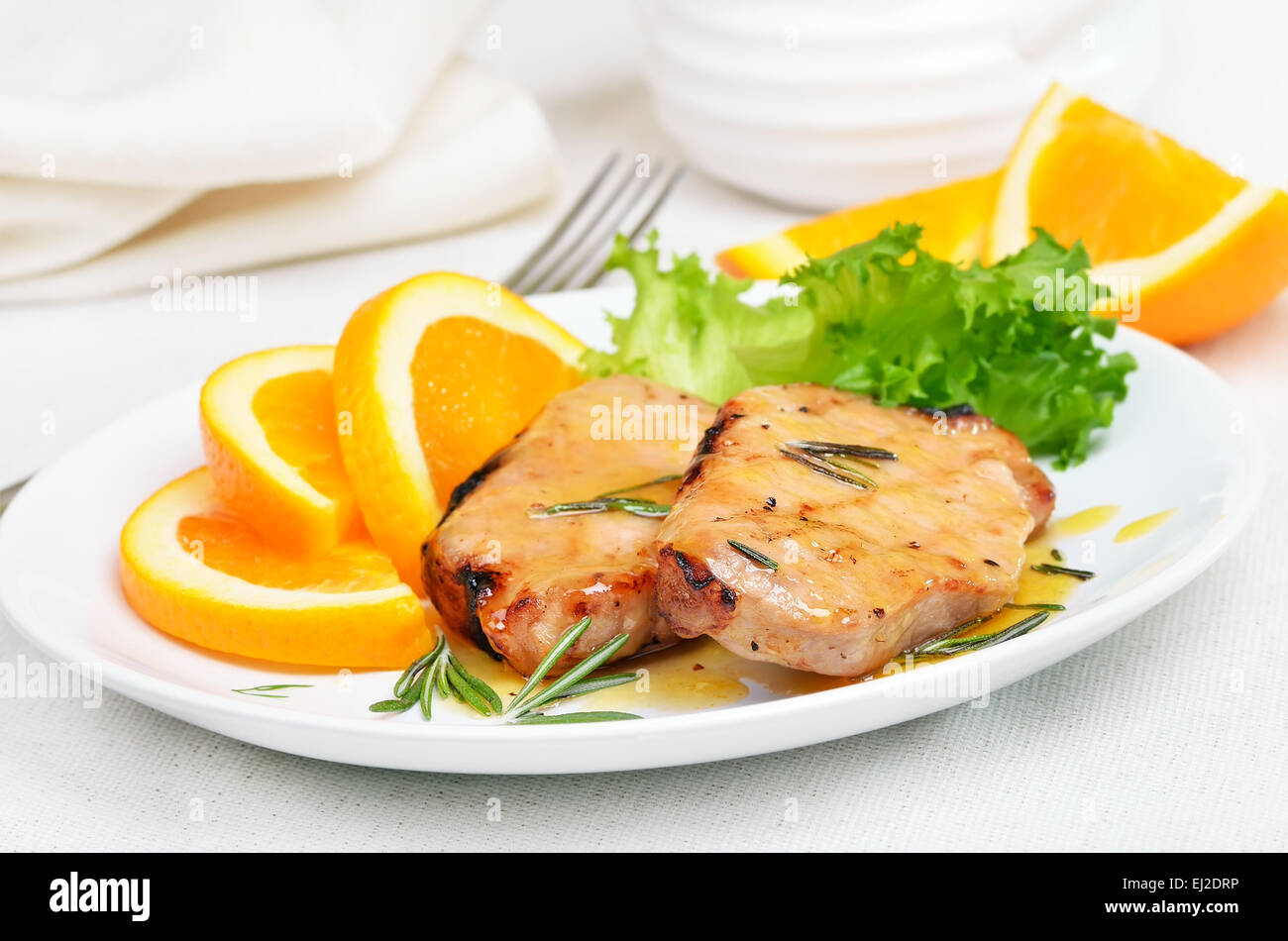 Côtelette de porc cuit au four avec sauce à l'orange on white plate Banque D'Images