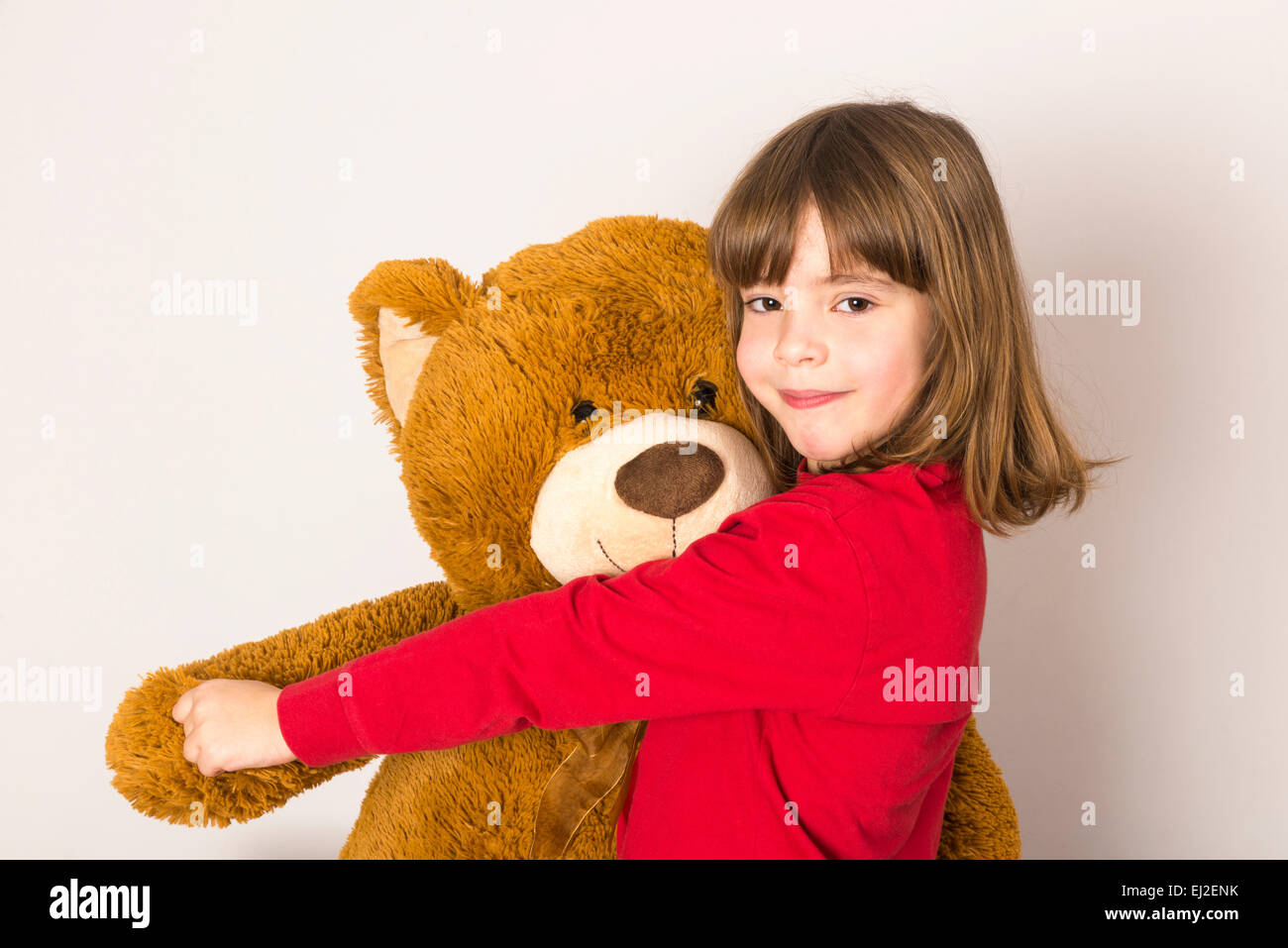 Petite fille danse avec son gros ours looking at camera sur fond blanc Banque D'Images