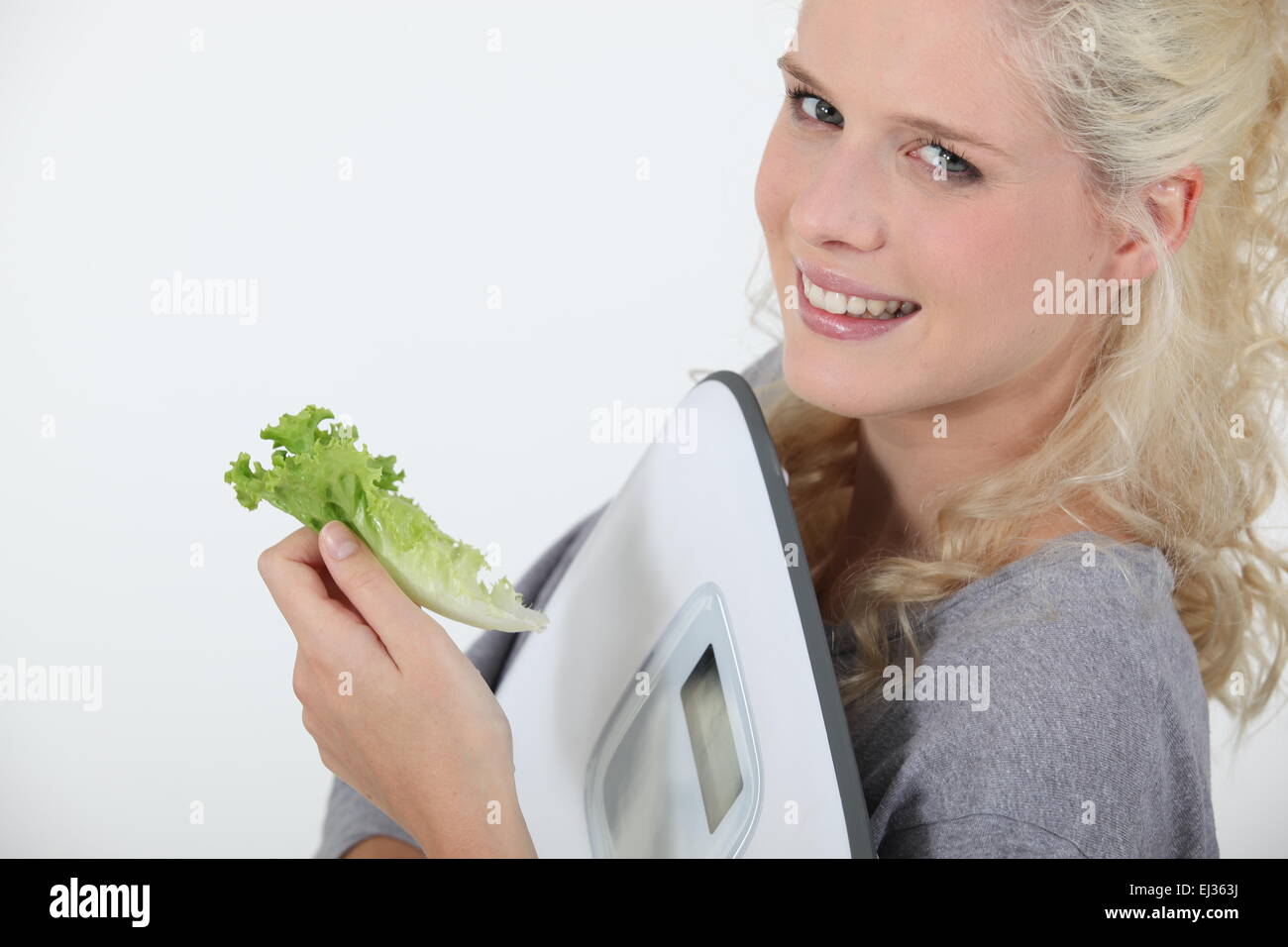 Portrait de face d'ange blond transportant des balances avec des feuilles de salade dans la main Banque D'Images