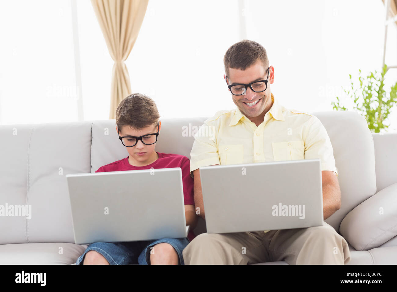 Père et fils portant des lunettes nouveauté while using laptop Banque D'Images