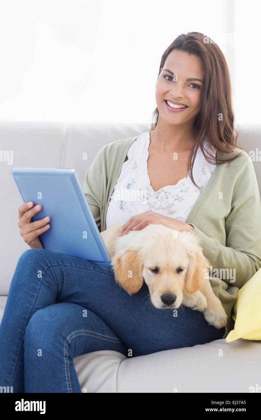 Femme avec chien using tablet computer on sofa Banque D'Images