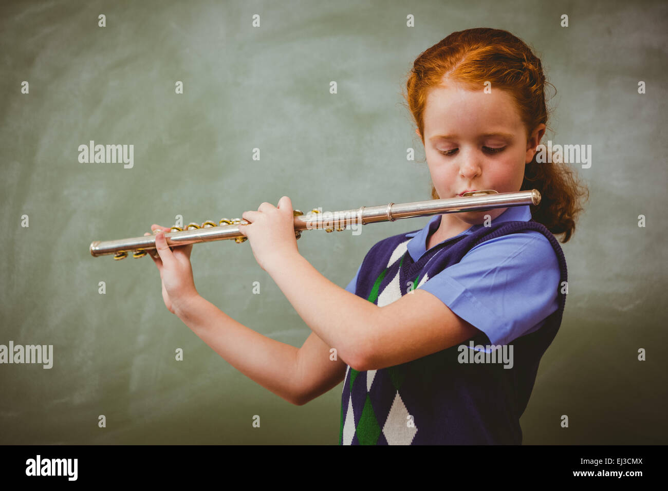 Cute little girl playing flute in classroom Banque D'Images