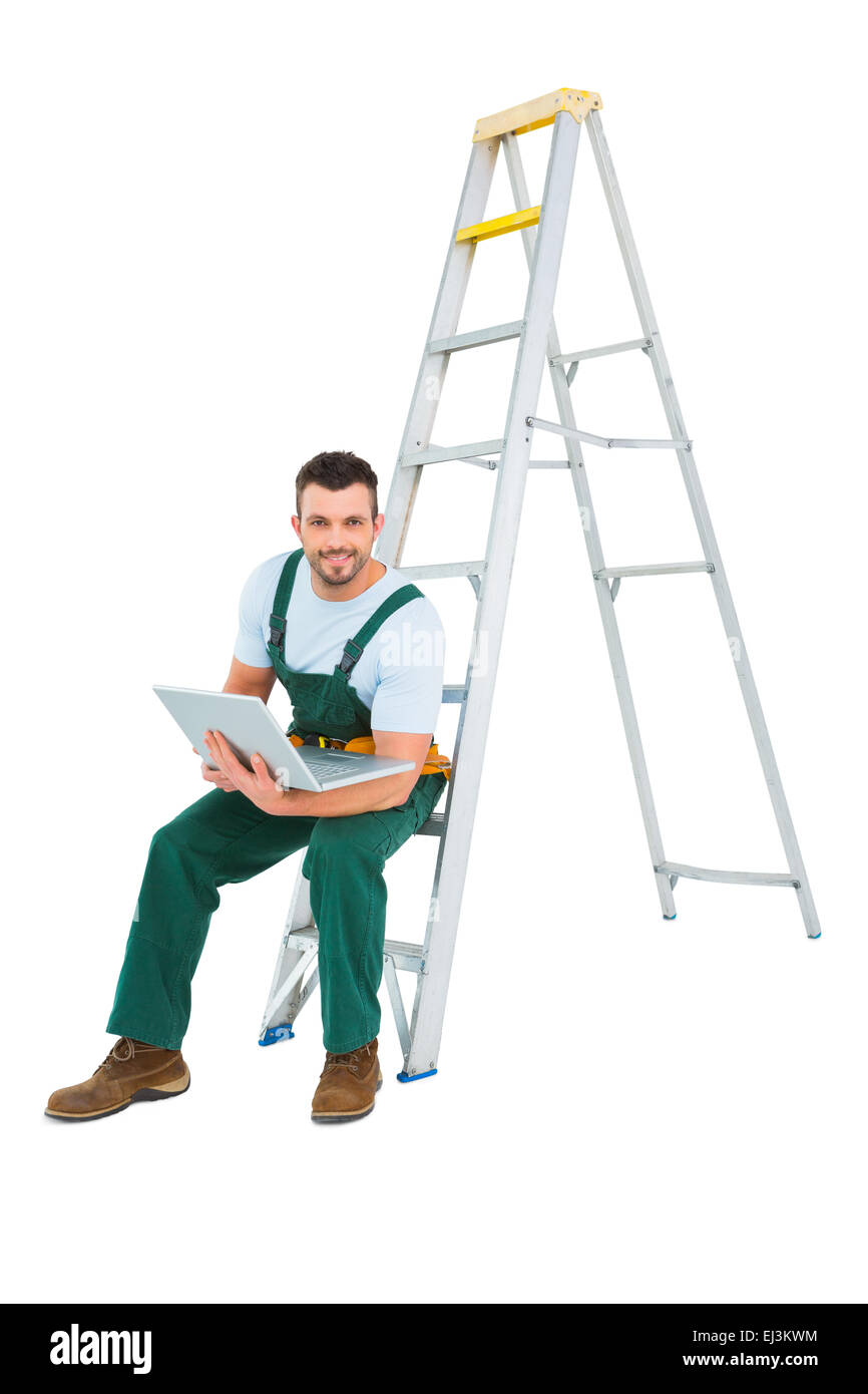 Carpenter assis sur échelle à l'aide de l'ordinateur portable Banque D'Images