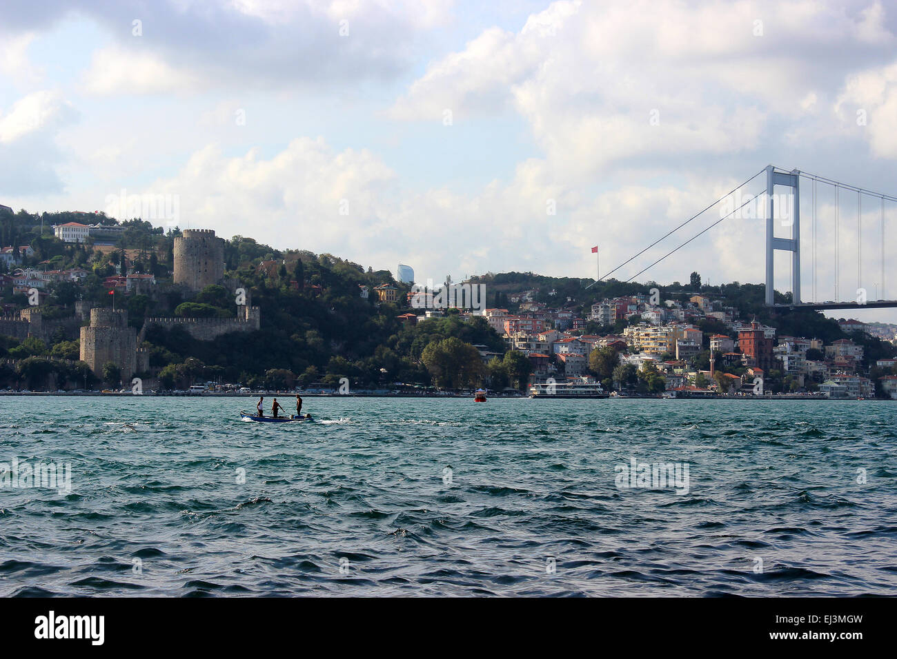 Trois bateliers debout sur un bateau dans l'affaire Bosphorus, Istanbul. Rumeli Hisari, deuxième pont du Bosphore (Fatih Sultan Mehmet Br.) derrière Banque D'Images