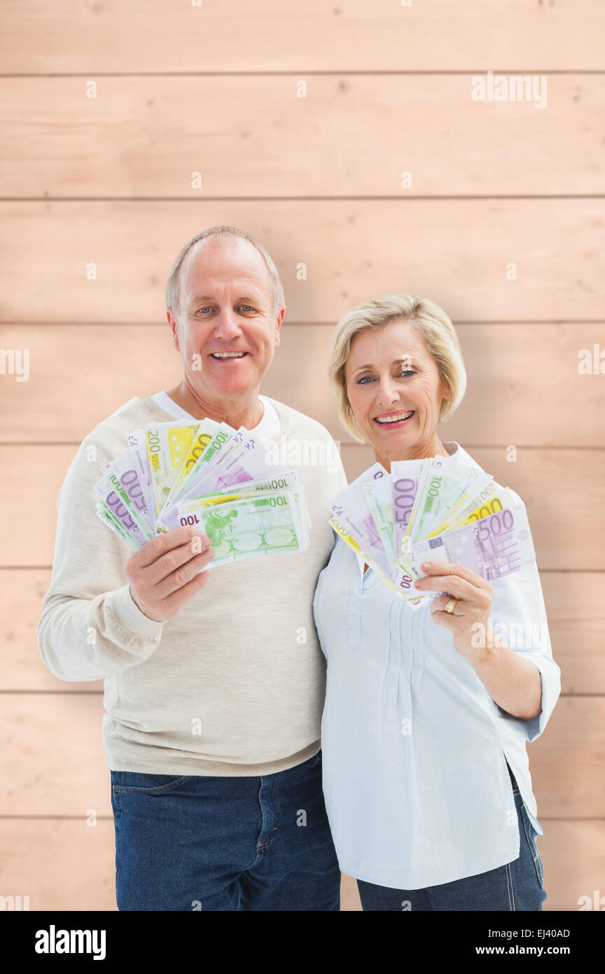 Composite image of mature couple smiling at camera montrant l'argent Banque D'Images