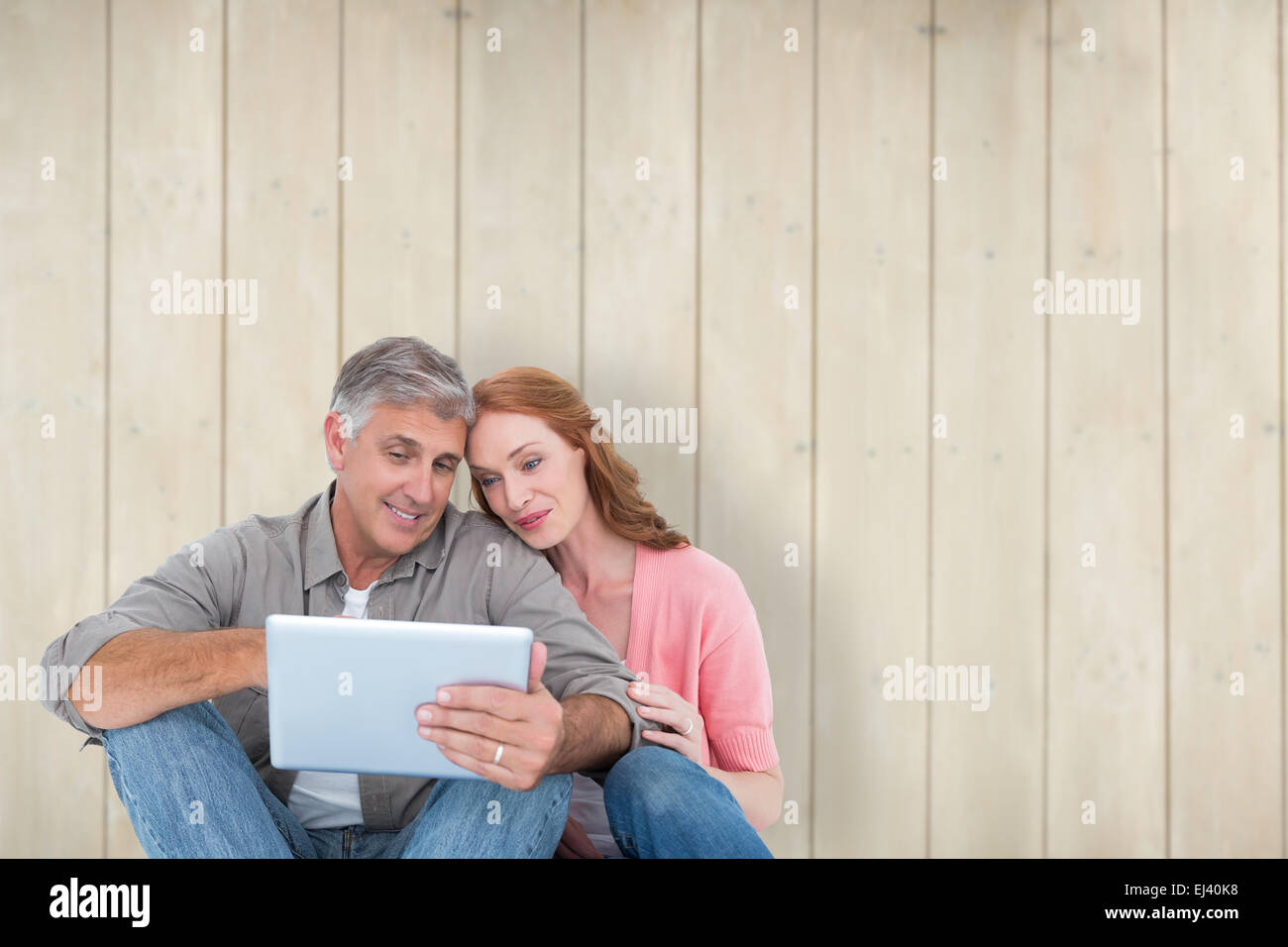 Image composite de casual couple assis à l'aide de tablet Banque D'Images