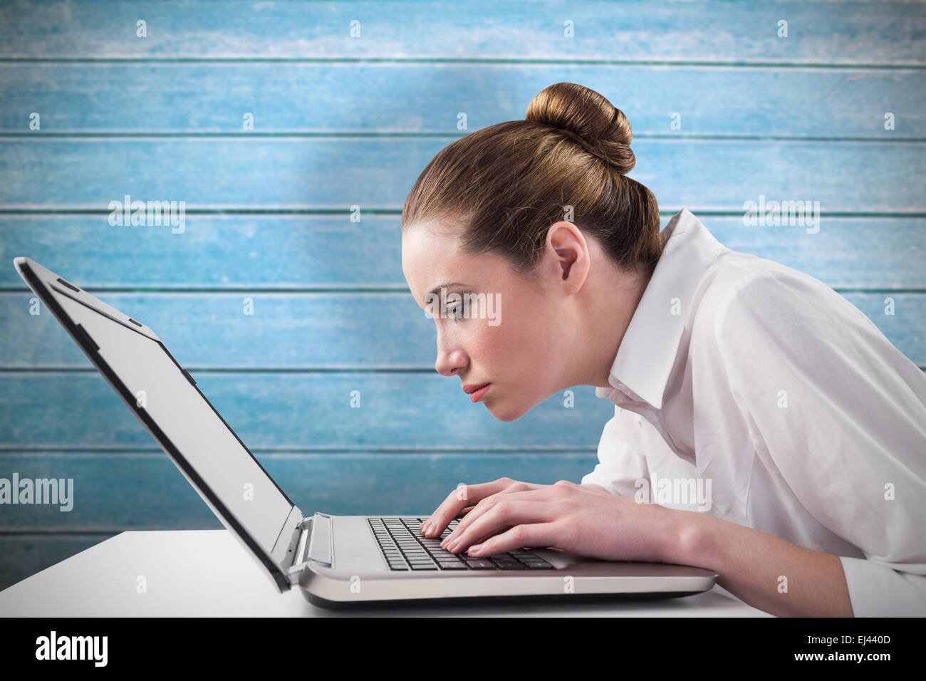 Image composite de businesswoman attentif typing on laptop Banque D'Images