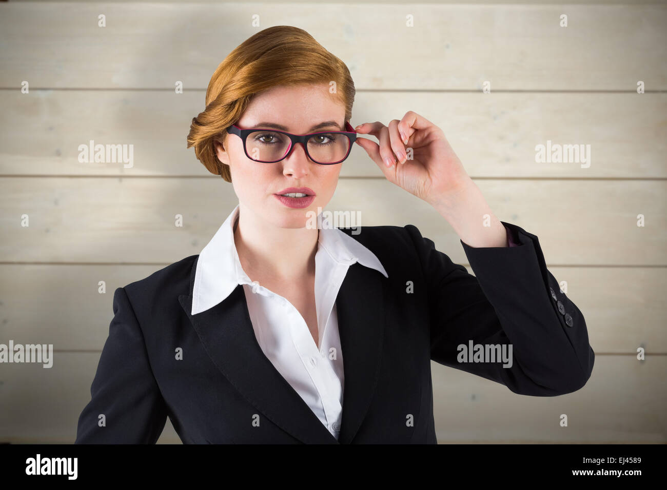 Image composite de redhead businesswoman touching ses lunettes Banque D'Images