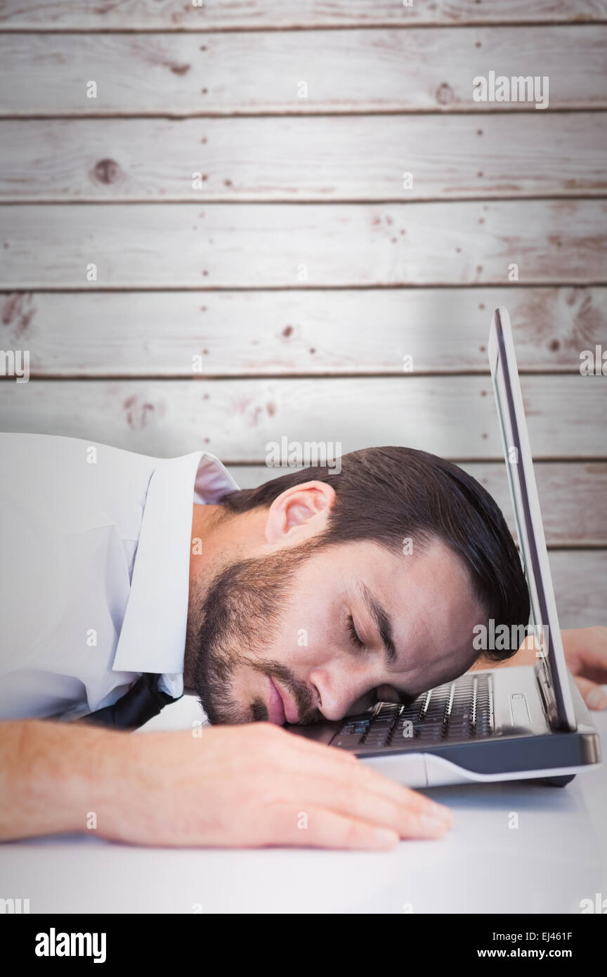 Image composite de businessman resting head on laptop keyboard Banque D'Images