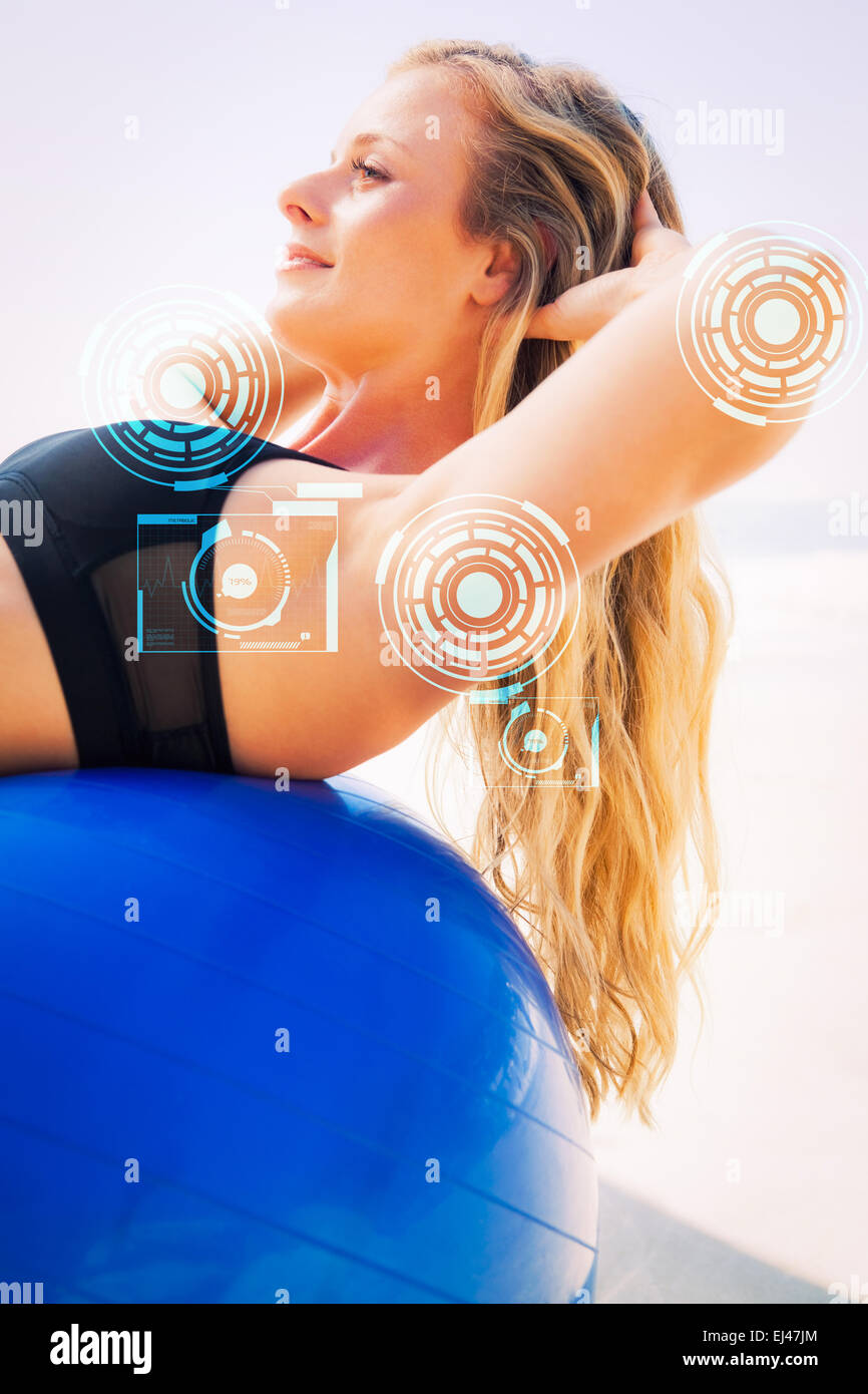 Image composite de la fit asseoir sur ups blonde faisant boule d'exercice à la plage Banque D'Images