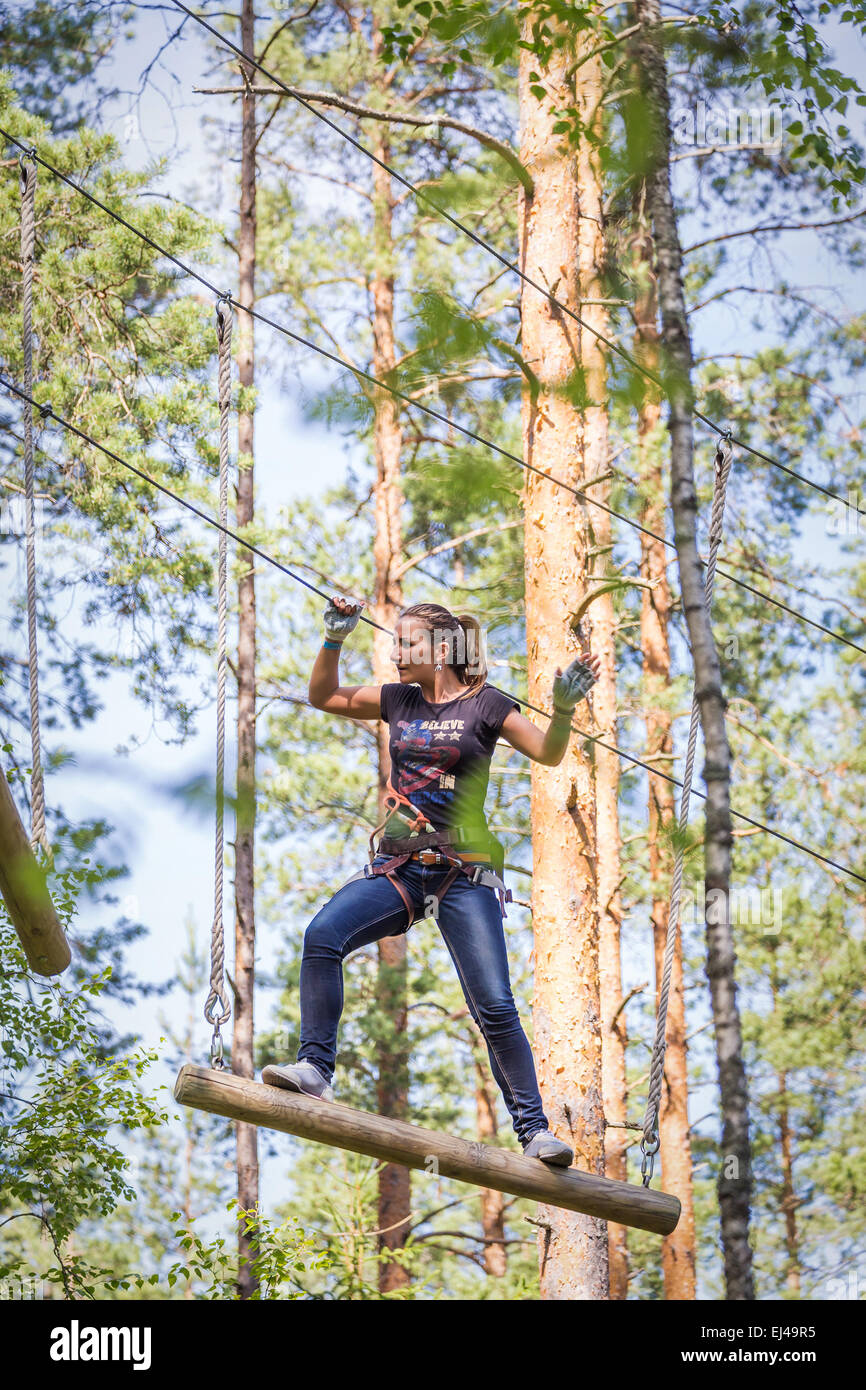 13 juillet 2014, la Russie, Saint-Petersbourg, parc aventure 'Norwegian wood'. Jeune femme courageuse de l'escalade dans un parc aventure Banque D'Images