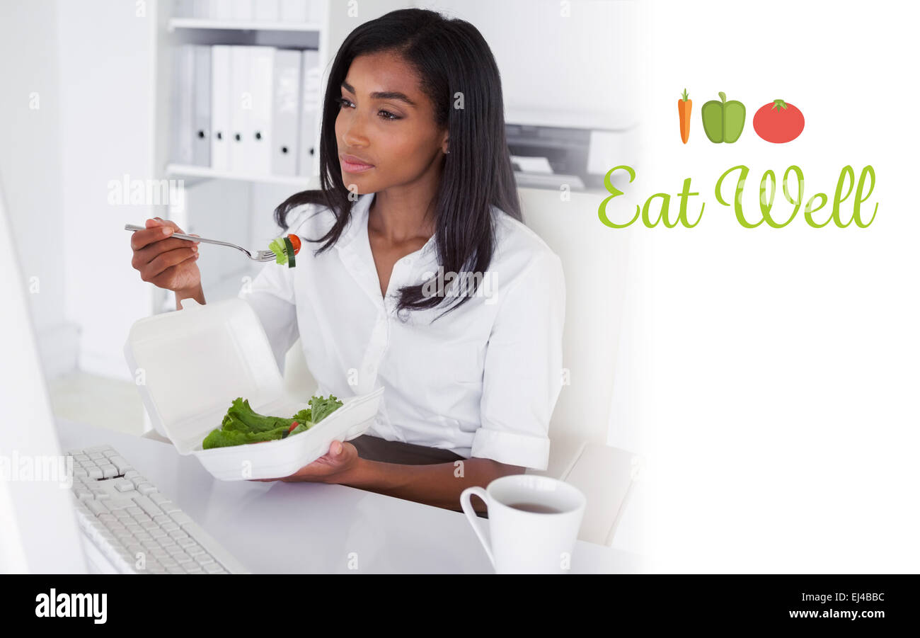 Bien manger contre jolie businesswoman eating a salad at her desk Banque D'Images