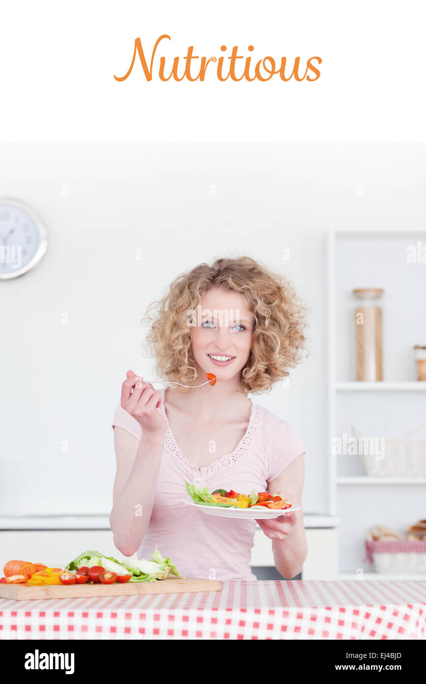 Contre nutritifs jolie blonde woman eating quelques légumes dans la cuisine Banque D'Images