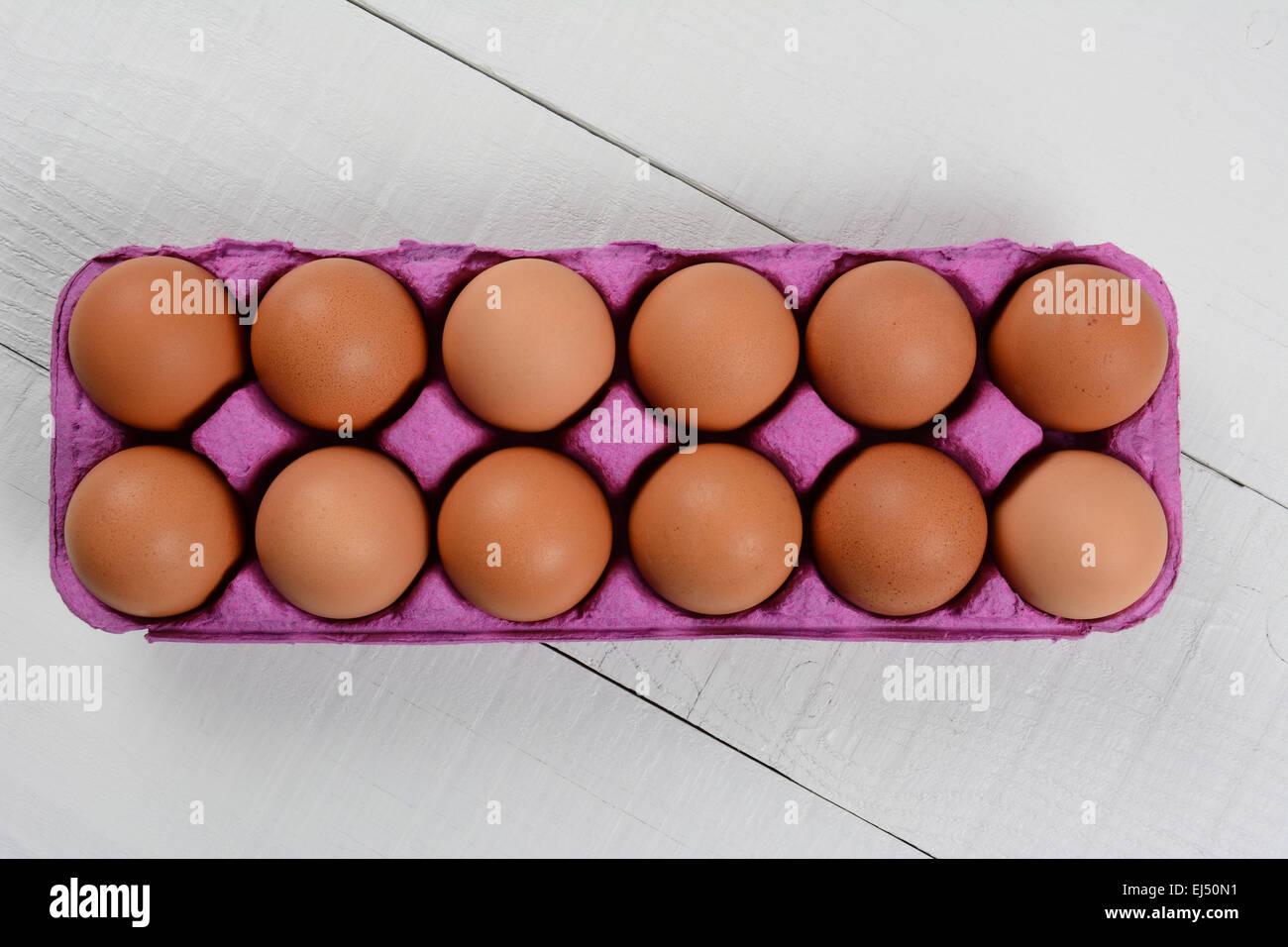 High angle shot d'une douzaine d'œufs dans un brun biologique carton rose sur une table rustique en bois blanc. Format horizontal avec co Banque D'Images