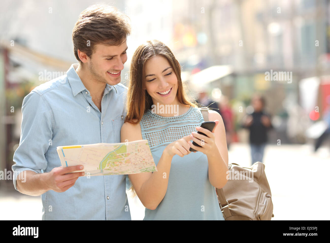 Couple de touristes consulting un guide de la ville et GPS du smartphone dans la rue rechercher endroits Banque D'Images