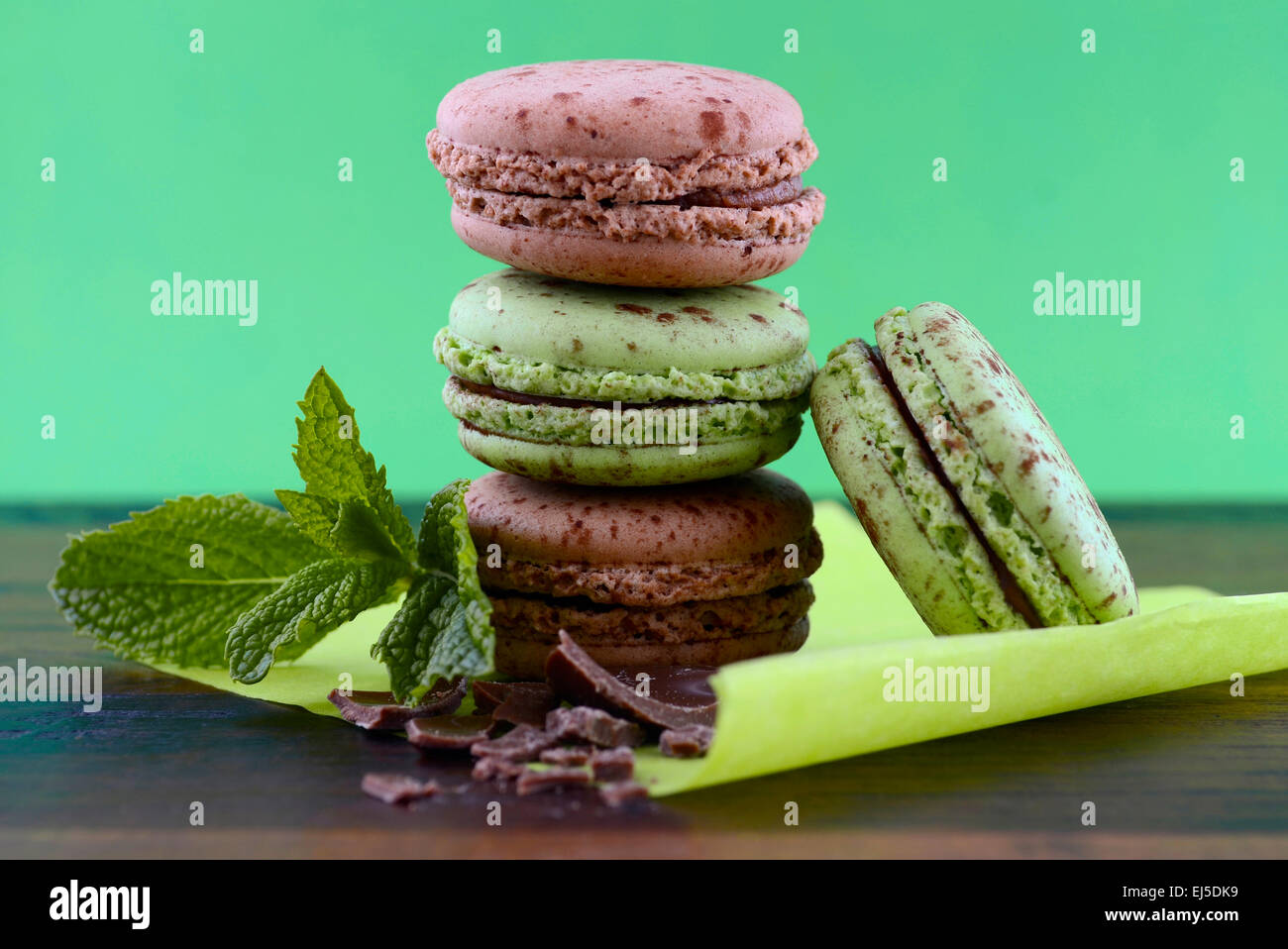 Le chocolat et les macarons saveur de menthe sur la table en bois sombre et fond vert. Banque D'Images