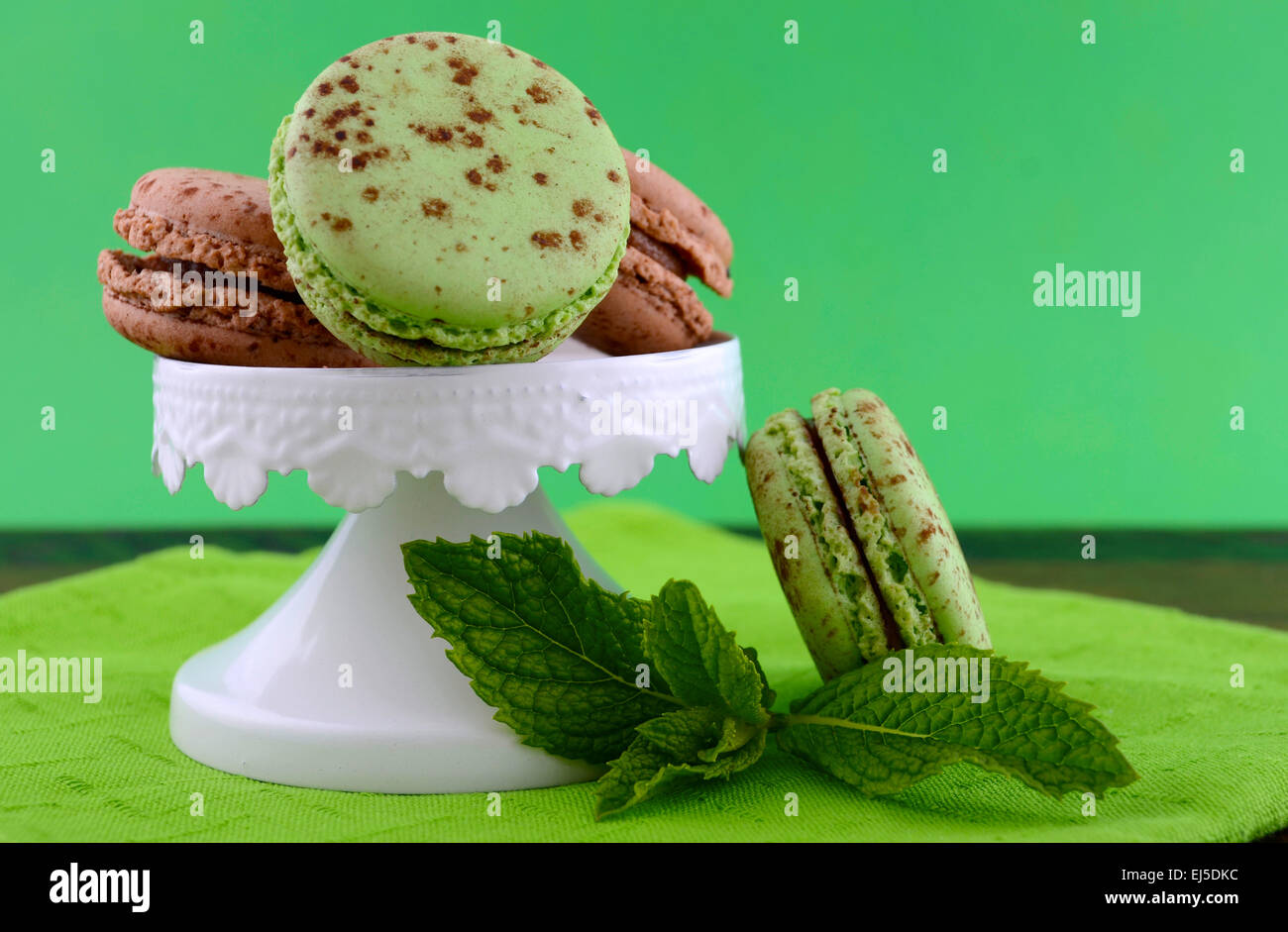Le chocolat et les macarons saveur de menthe sur la table en bois sombre et fond vert. Banque D'Images