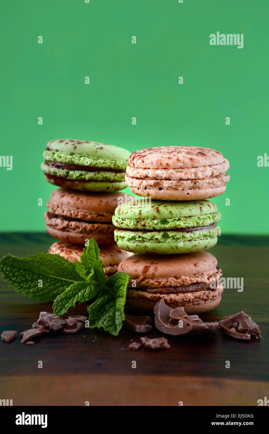 Le chocolat et les macarons saveur de menthe sur la table en bois sombre et fond vert. Banque D'Images