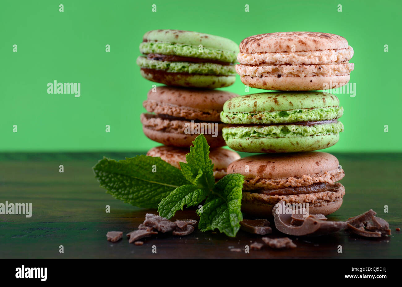 Le chocolat et les macarons saveur de menthe sur la table en bois sombre et fond vert. Banque D'Images