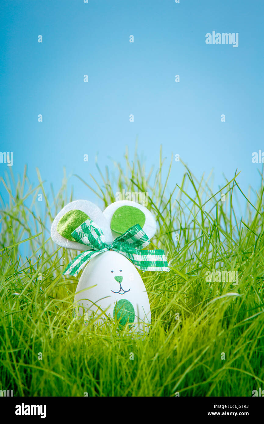 Oeufs de Pâques décorés dans l'herbe sur fond bleu Banque D'Images
