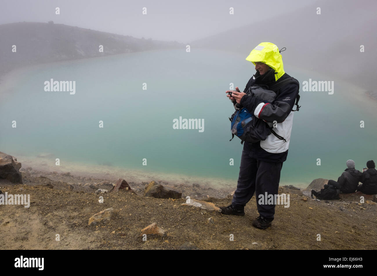 Les promeneurs sur le Tongariro alpine crossing arrêter au Blue Lake, dans des conditions climatiques extrêmes, la Nouvelle-Zélande. Banque D'Images