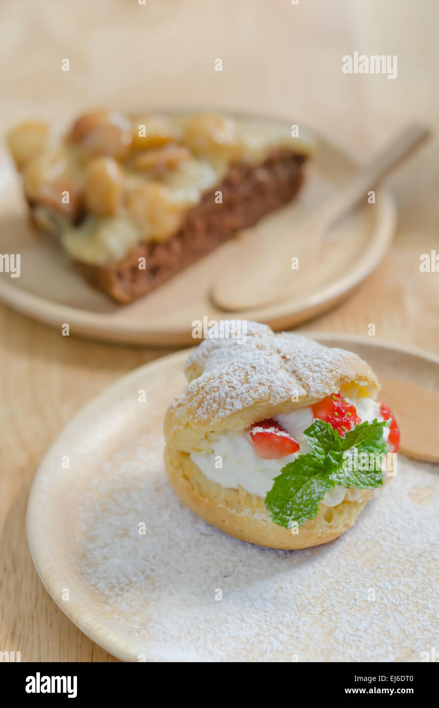 Des fraises fraîches choux crème sur le plat en bois Banque D'Images