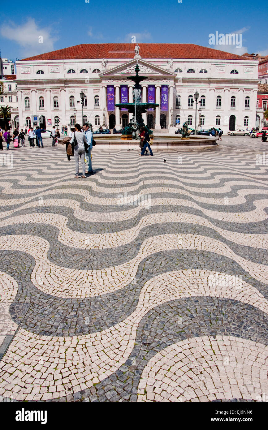 Pavés de carreaux portugais ondulées à Lisbonne, sur la place Rossio avec Théâtre National Dona Maria II et fontaine baroque. Banque D'Images