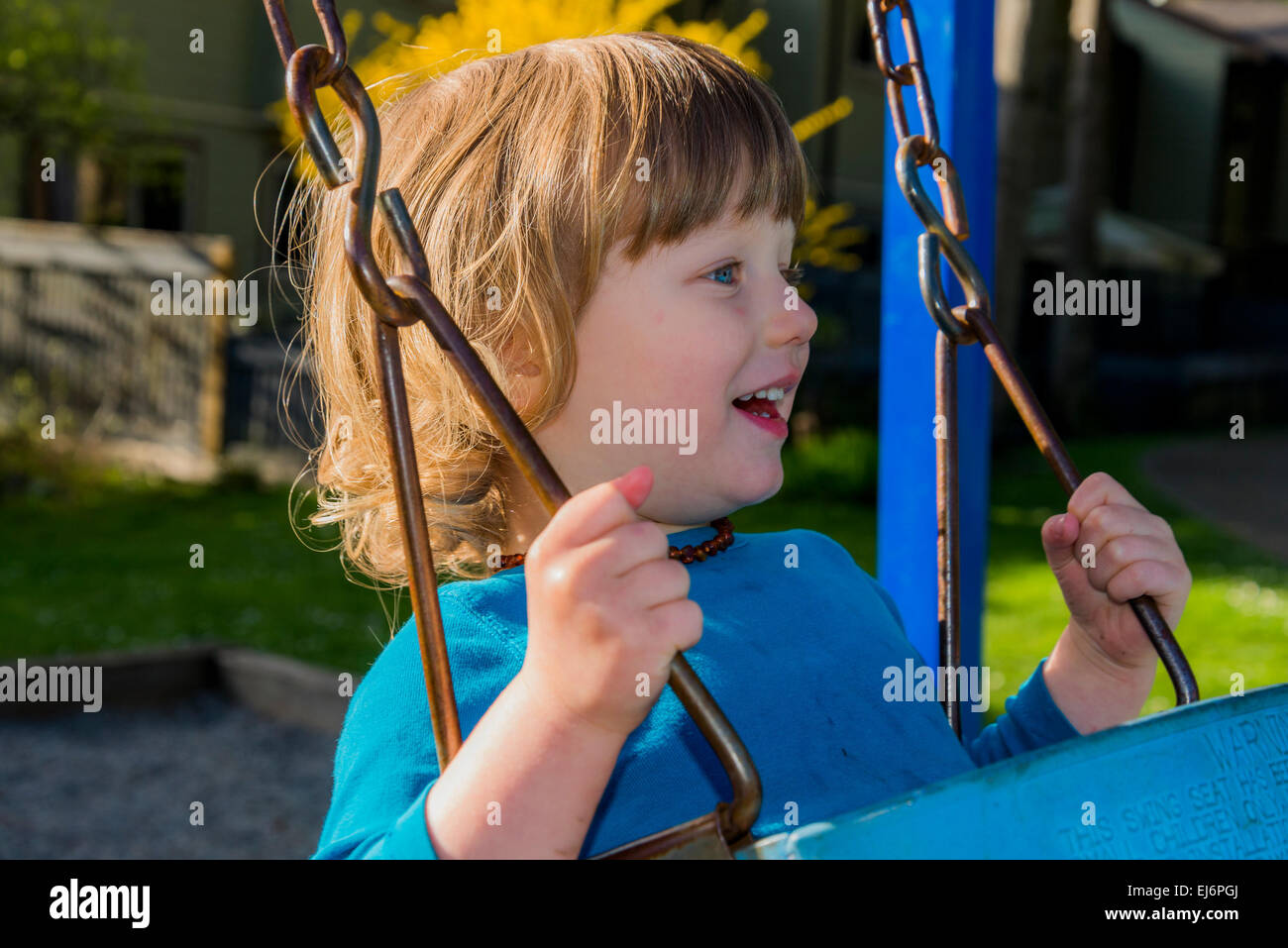 Happy boy on playground swing. Banque D'Images