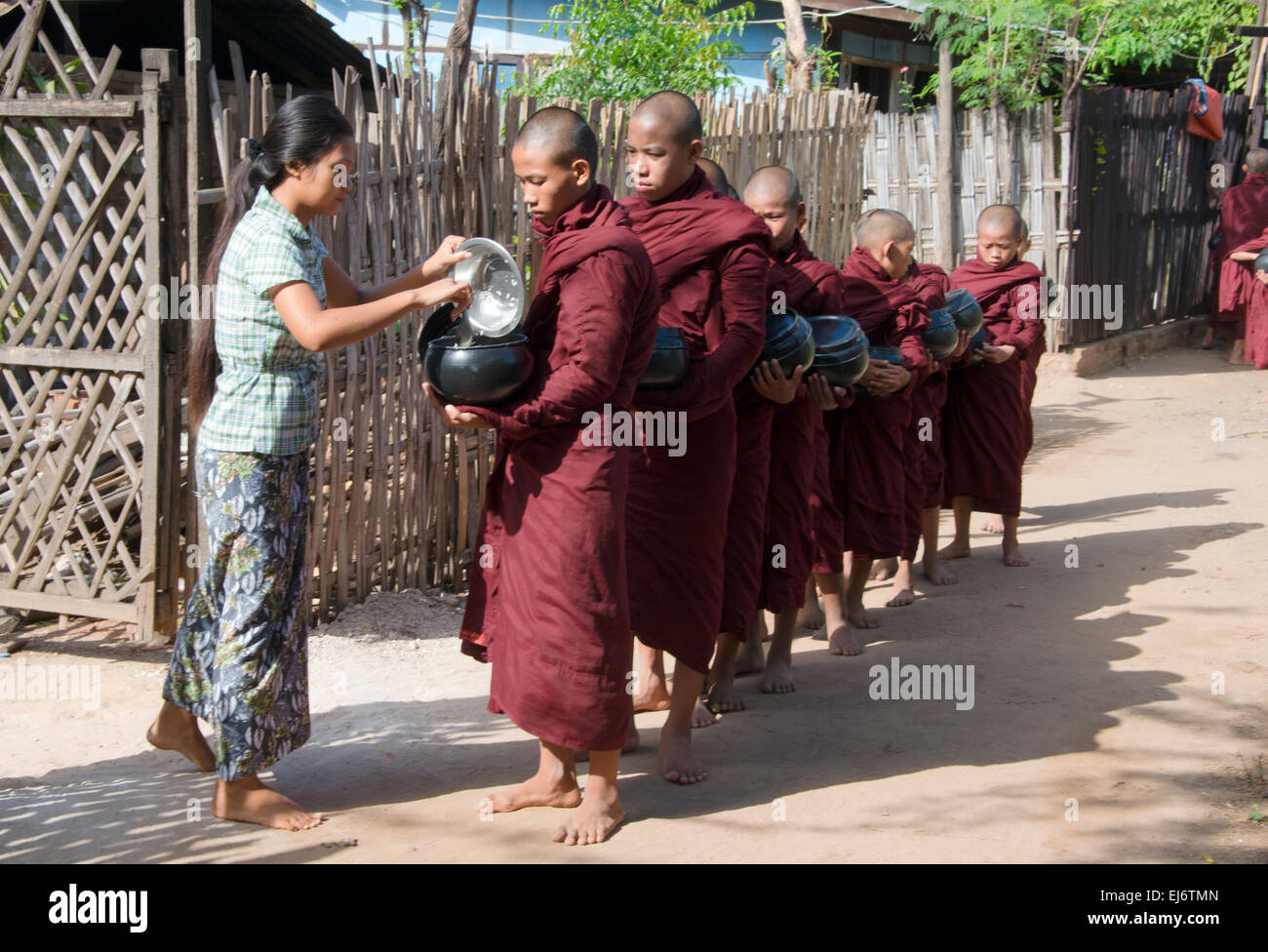 Femme de donner des aumônes la nourriture aux moines attendent en ligne, Bagan, Mandalay, Myanmar Région Banque D'Images