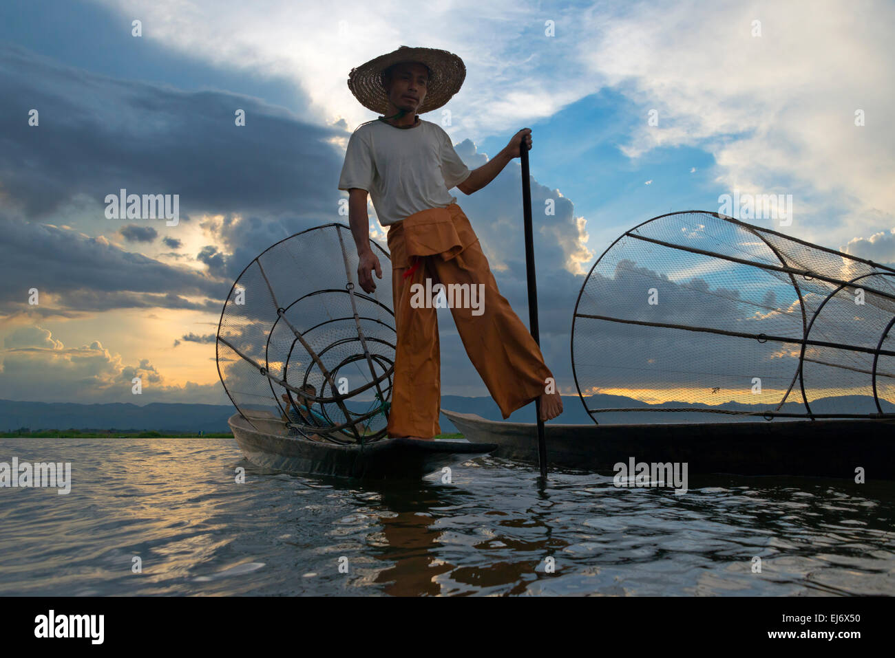 Barque de pêcheur ethnie Intha avec jambe au coucher du soleil sur le lac Inle, l'État de Shan, Myanmar Banque D'Images