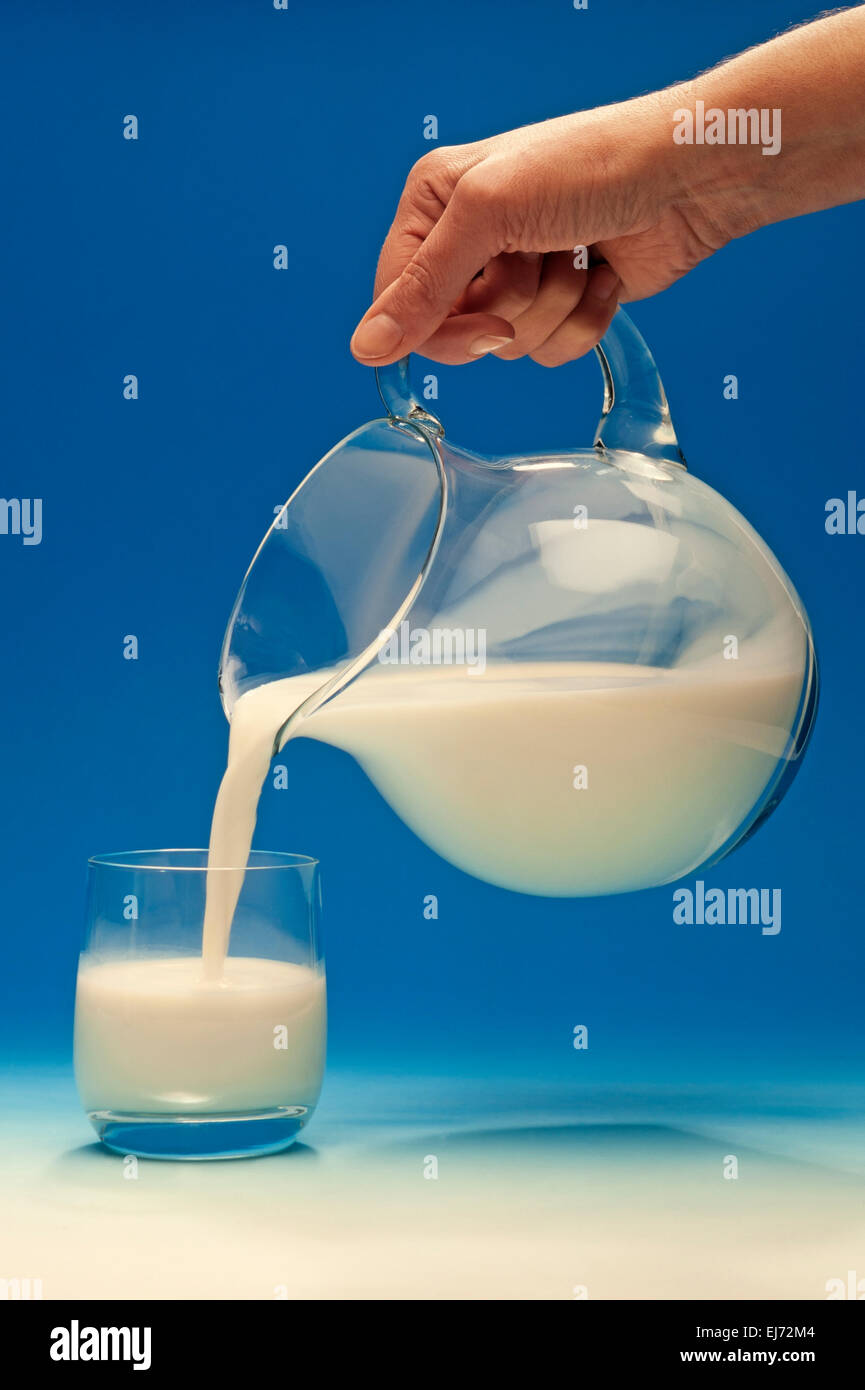 Verser le lait de la main une cruche dans un verre Banque D'Images