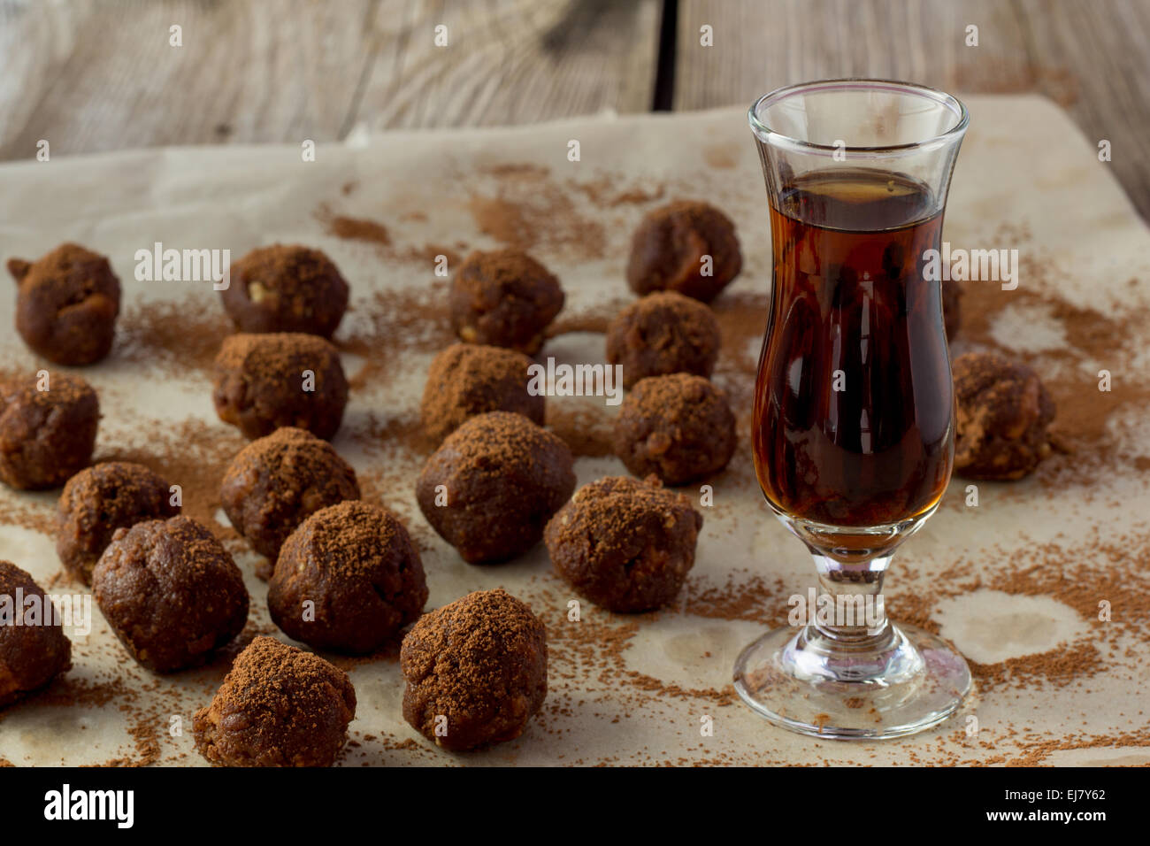 Photo de petit verre de cognac et des bonbons table en bois Banque D'Images