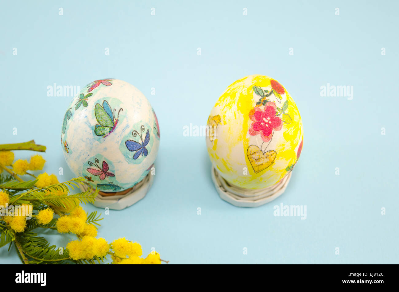 Découpage des œufs de Pâques peints à la main et mimosa sur bleu backrground Banque D'Images
