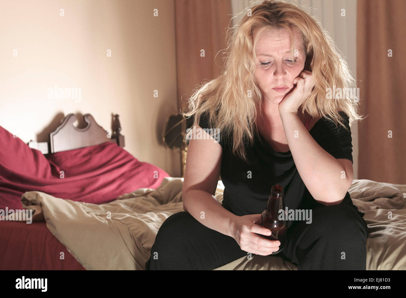 Une femme alcoolique de boire une bière dans sa chambre. Banque D'Images