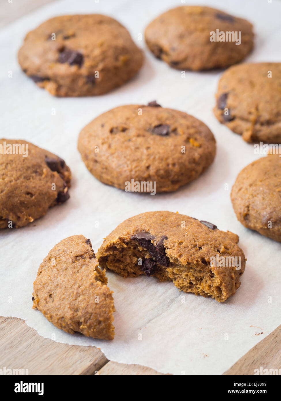 Vegan de grains entiers d'épeautre cookies potiron doux avec des copeaux de chocolat sur une feuille de papier cuisson. Banque D'Images