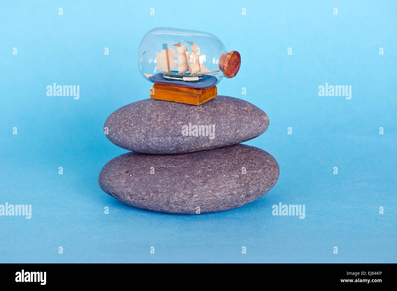 Petit bateau voilier modèle dans le flacon en verre sur fond azur et de pierre de la mer Banque D'Images