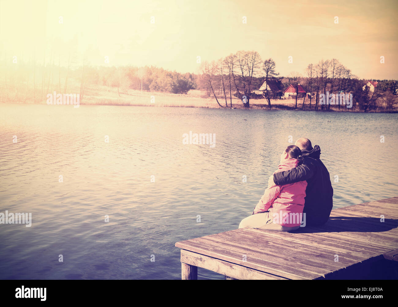 Retro photo filtrée d'un couple sitting on pier by lake. Banque D'Images