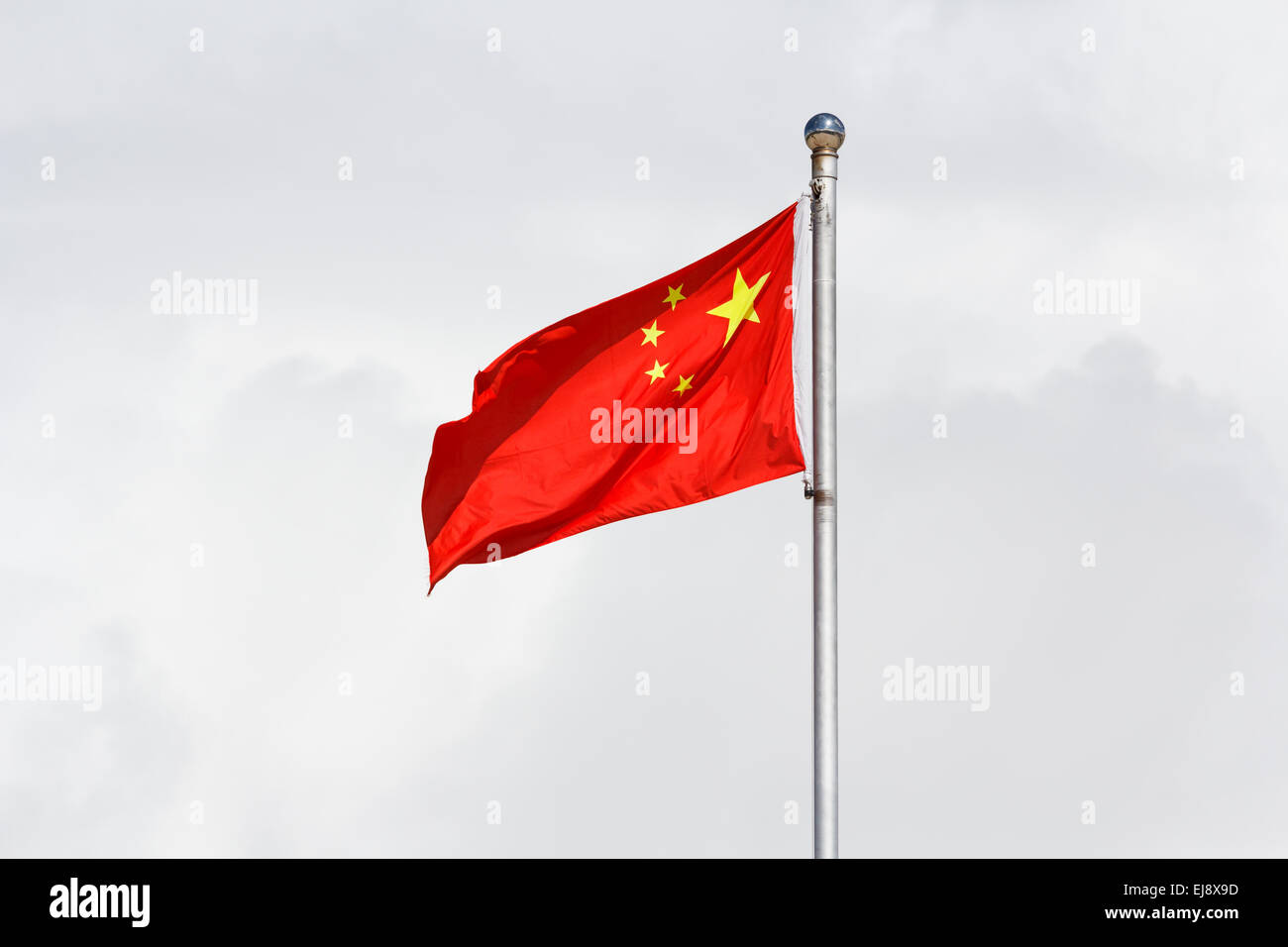 Brandissant le drapeau chinois sur mât aluminium contre fond nuageux Banque D'Images