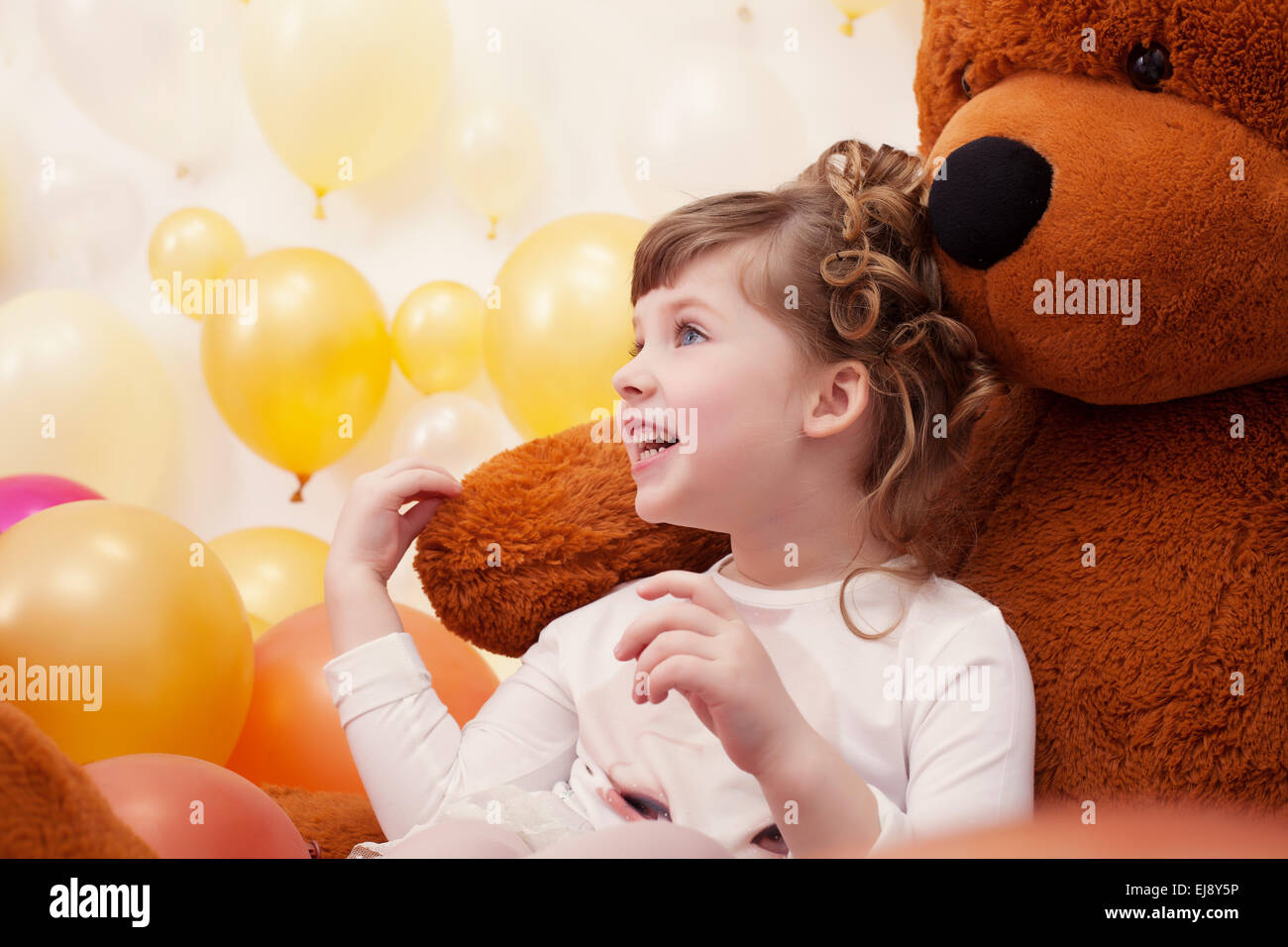 Petite fille joyeuse posing hugging bear peluche Banque D'Images