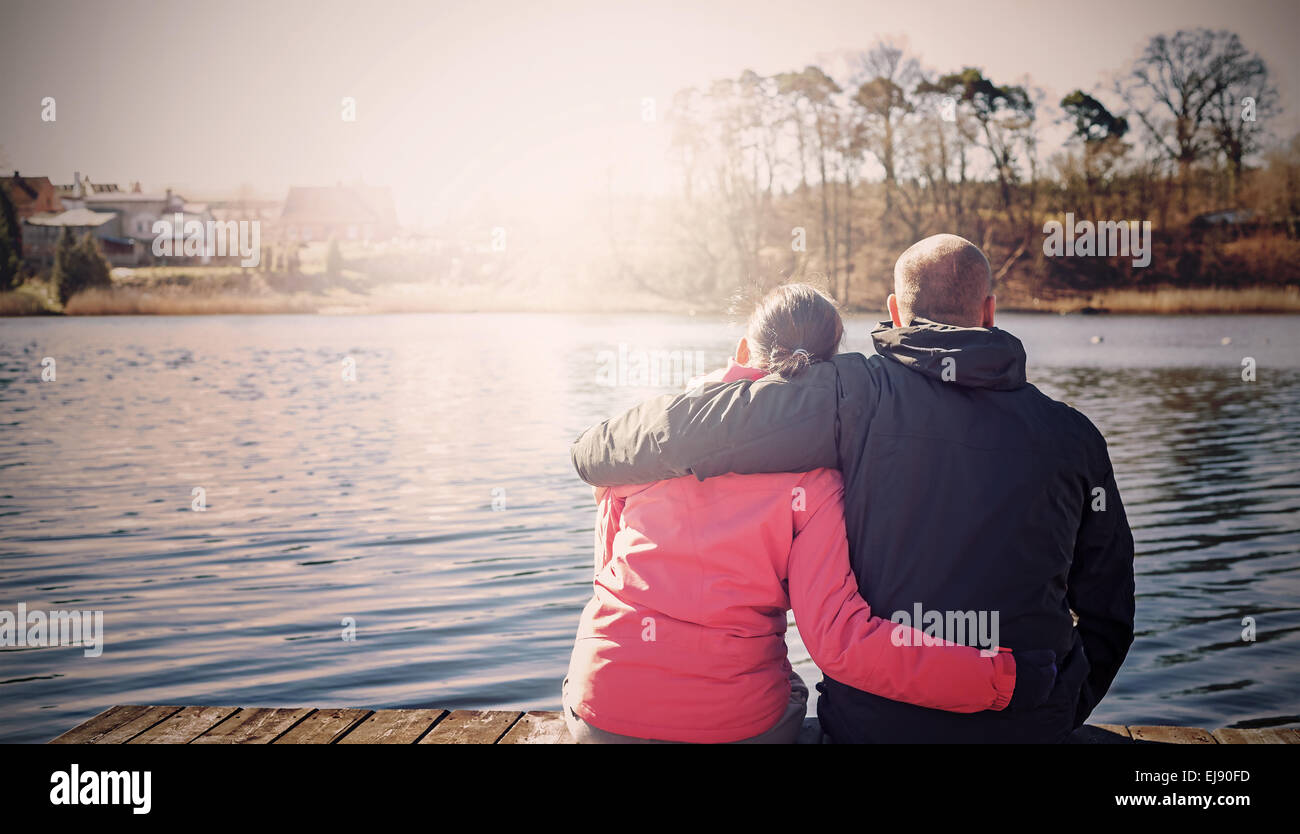 Filtrée Retro photo d'un couple sitting on wooden pier par lac. Banque D'Images