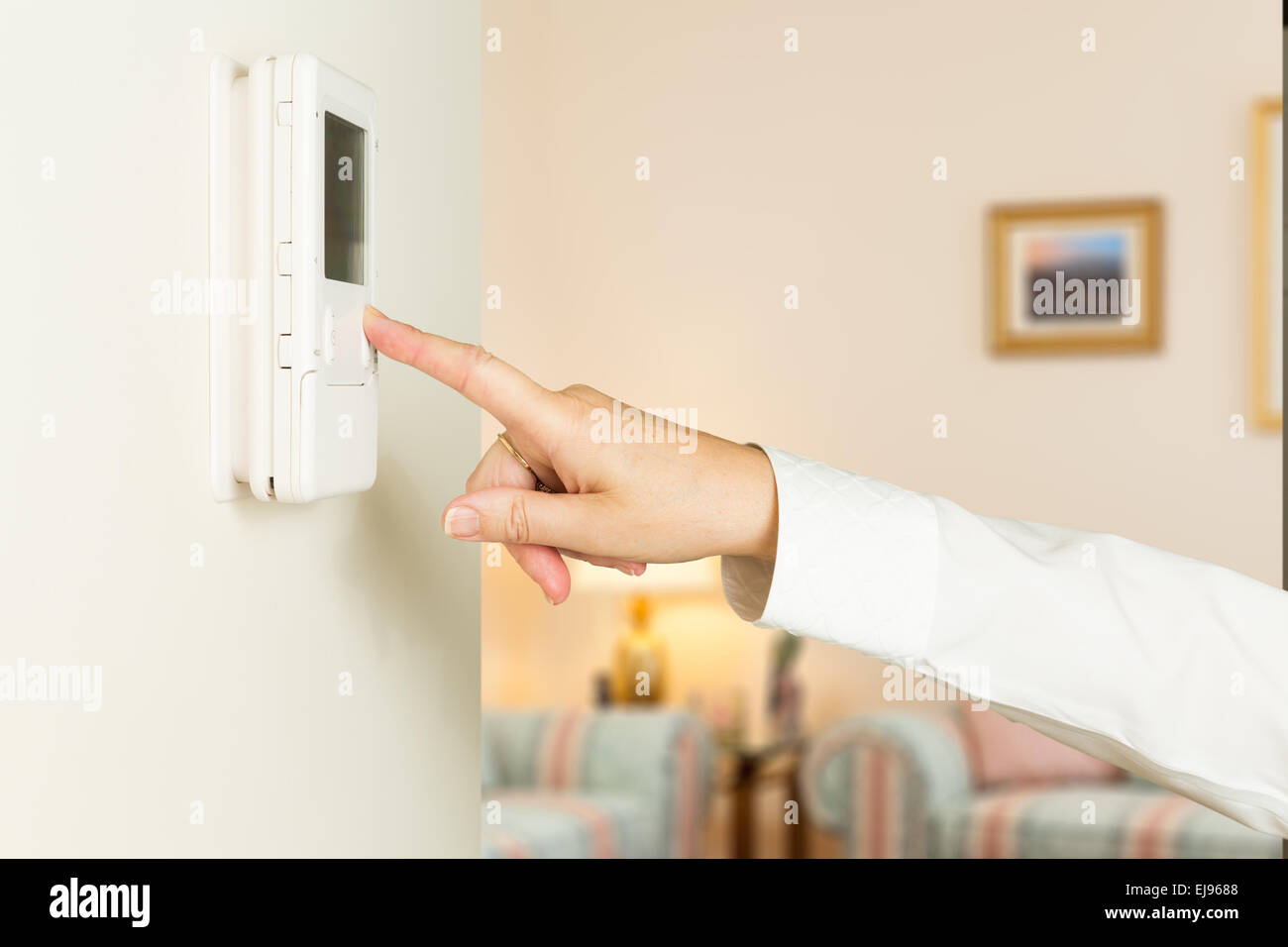 Young lady appuyant sur thermostat moderne Banque D'Images