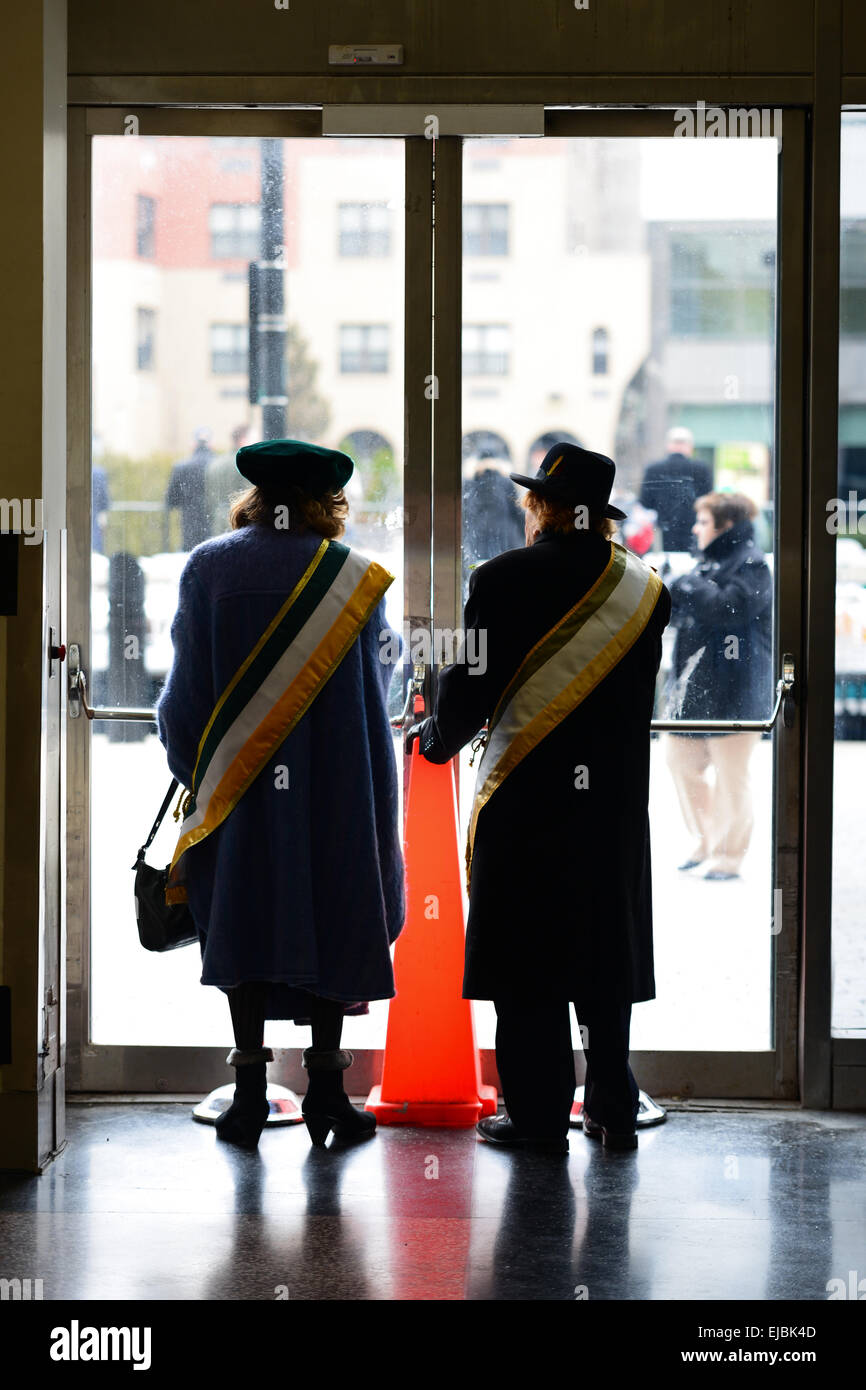 Deux personnes regardant le le jour de la Saint Patrick 2013 Parade de derrière une porte en verre loin du froid. Newark, New Jersey. USA Banque D'Images