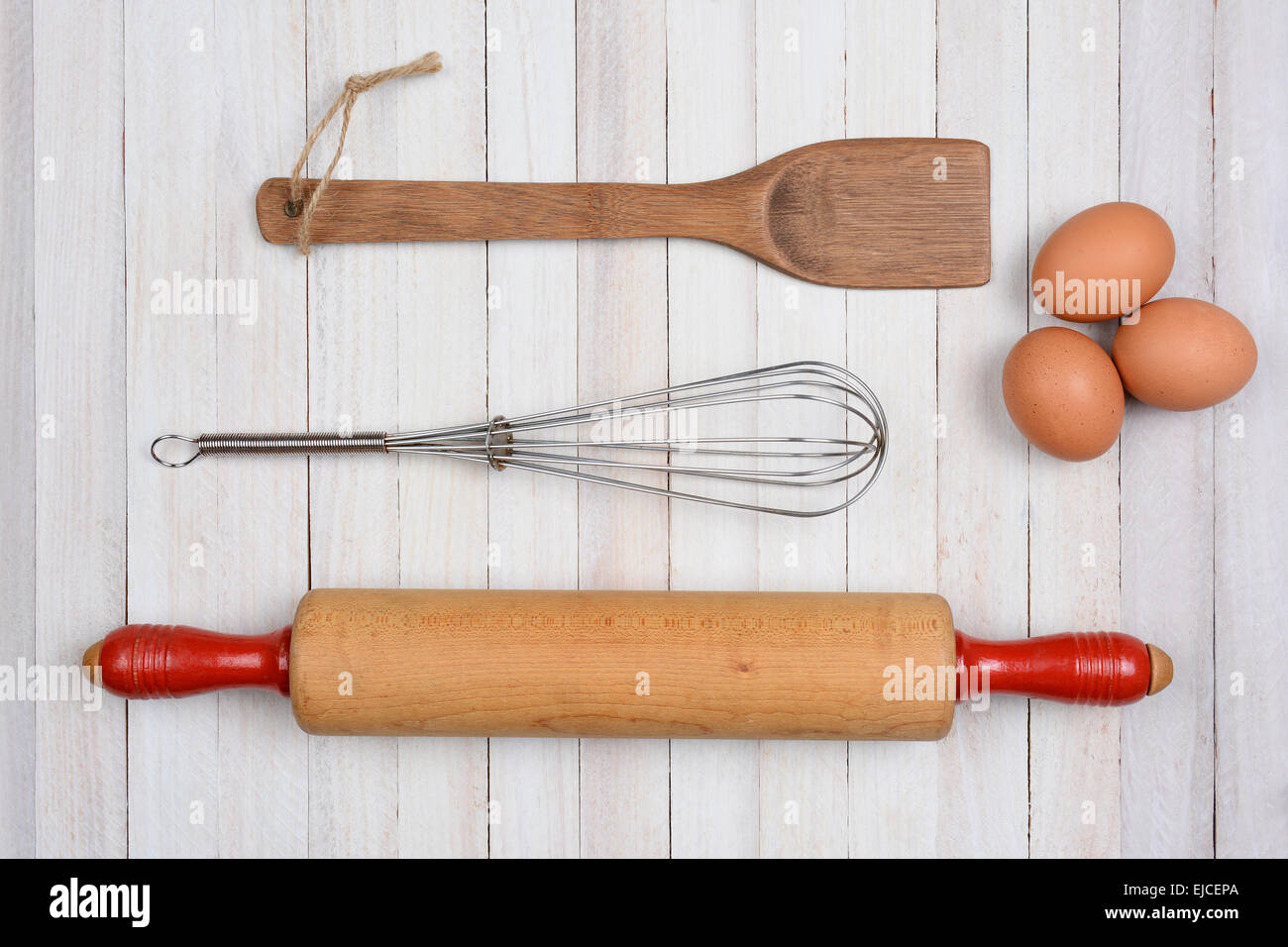 High angle droit d'un rouleau à pâtisserie, Ustensiles de cuisine et trois oeufs brun sur une table de cuisine en bois rustique. Banque D'Images