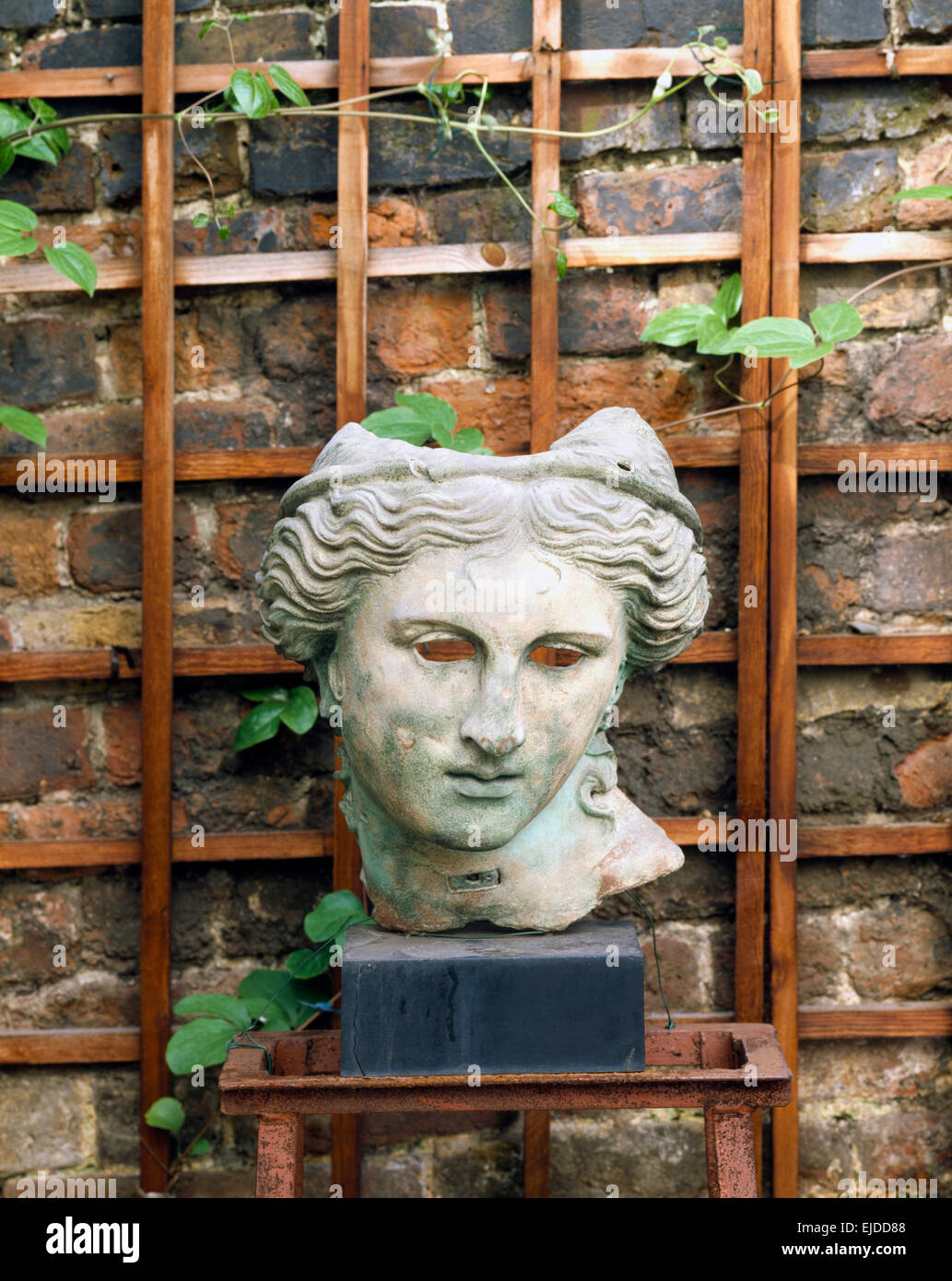 La sculpture sur pierre la tête contre mur avec treillis en bois Banque D'Images
