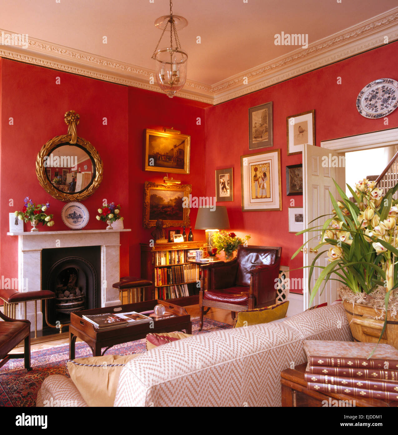 Collection de photos sur les murs des années 90 rouge salon avec cheminée en marbre au-dessus de miroir doré Banque D'Images