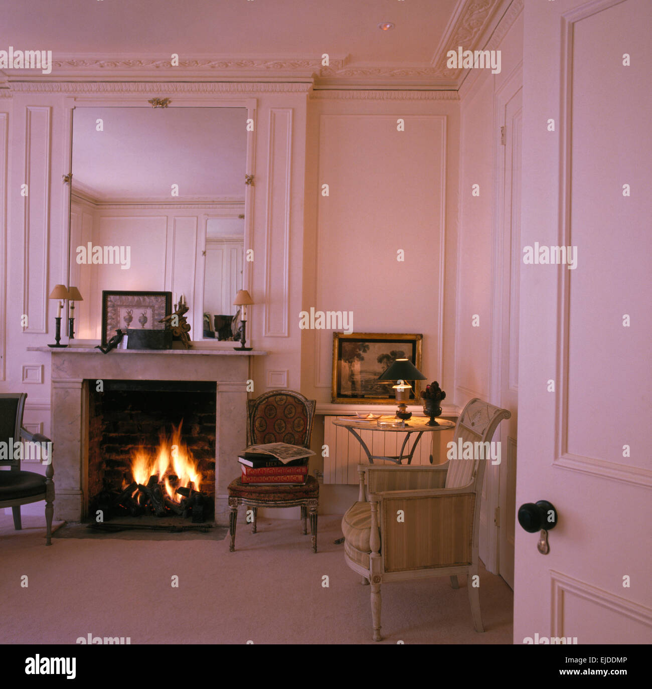 Grand miroir au-dessus de cheminée avec feu allumé dans d'élégantes  boiseries blanc salon français Photo Stock - Alamy