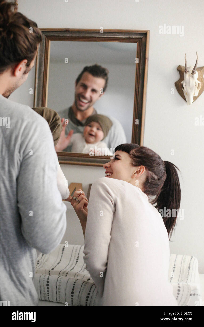 Un père et une mère avec son bébé, à la recherche dans le miroir. Banque D'Images