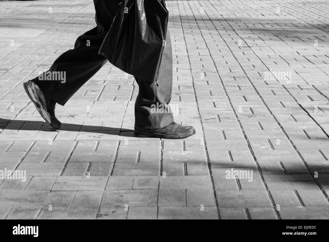 Un homme marche seul avec vieilles chaussures et un sac en plastique Banque D'Images