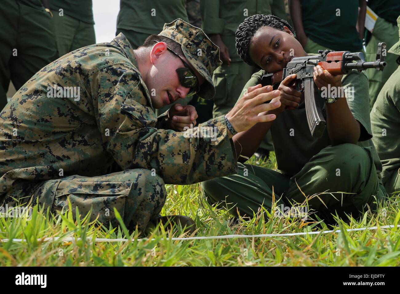 Un Marine américain avec l'outillage spécial air-sol marin crise Response-Africa Groupe de travail contribue à un park ranger tanzanien visent un fusil d'assaut AKM au cours d'un combat de classe d'adresse au tir au Selous 3 Mars, 2015 dans Matambwe, Tanzanie. Les marines sont des park rangers infantry tanzanien d'enseignement des compétences telles que les patrouilles, les tactiques offensives, la navigation terrestre et montées à l'aide à la lutte contre le trafic illicite. Banque D'Images