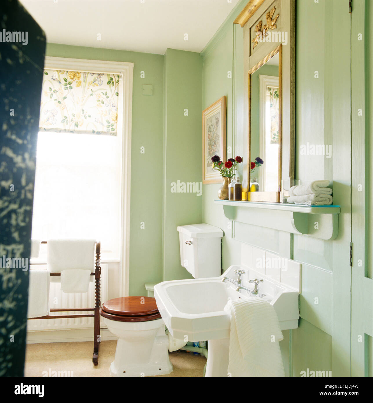 Vert pastel blanc salle de bains avec lavabo et toilettes avec siège en bois Banque D'Images